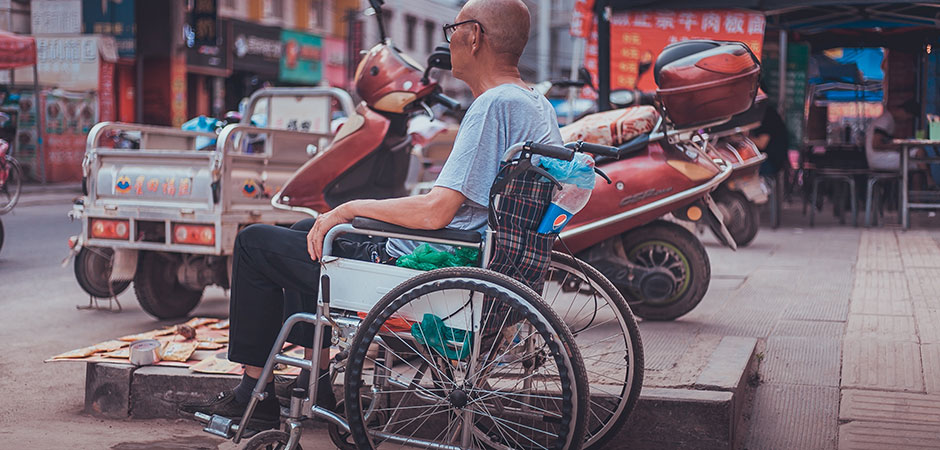 Man sitting in a wheelchair on a street in China.
