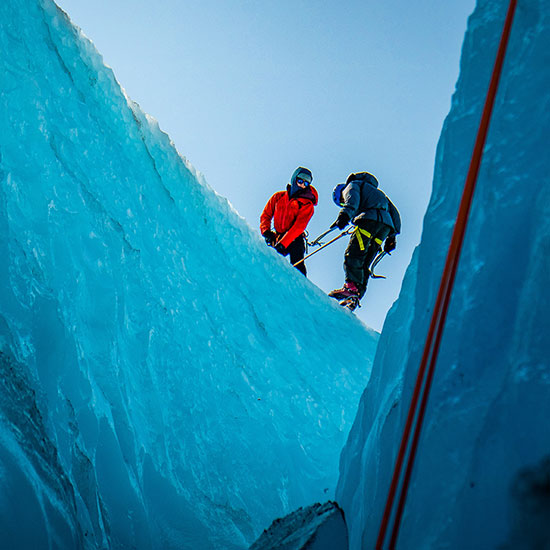 An image of two people climbing down a glacier on a guided tour.