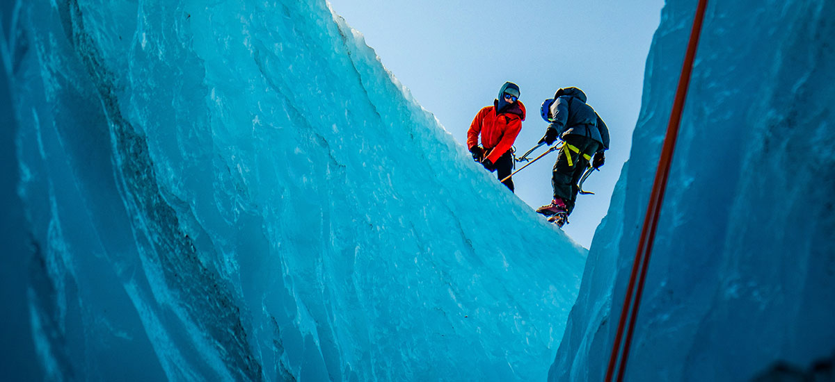 An image of two people climbing down a glacier on a guided tour.