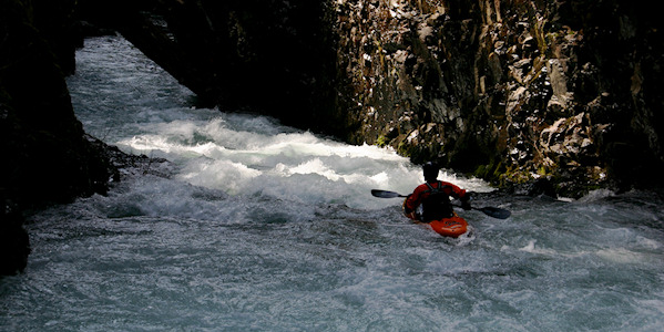 Kayaking near rocks wearing a helmet