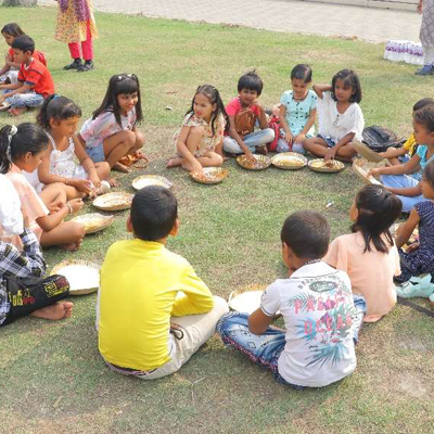 Kids sit around eating together, Eco Park, India