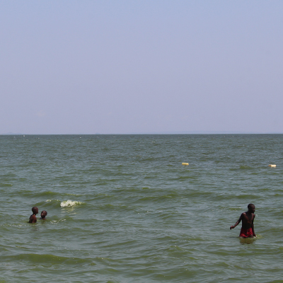 Kids seat down to eat a meal by the ocean at Entebbe beach